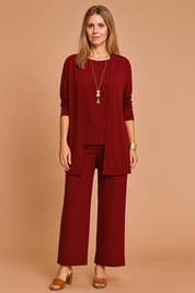 Three-piece dark burgundy women's outfit featuring a long-sleeve open-front cardigan, sleeveless matching blouse, and wide-leg ankle-length trousers in smooth solid fabric, styled with brown block-heel sandals and gold jewelry.