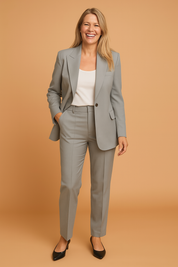 Tailored light gray women’s pantsuit with a structured blazer and matching high-waisted trousers, styled over a white tank top, ideal for business or formal wear.
