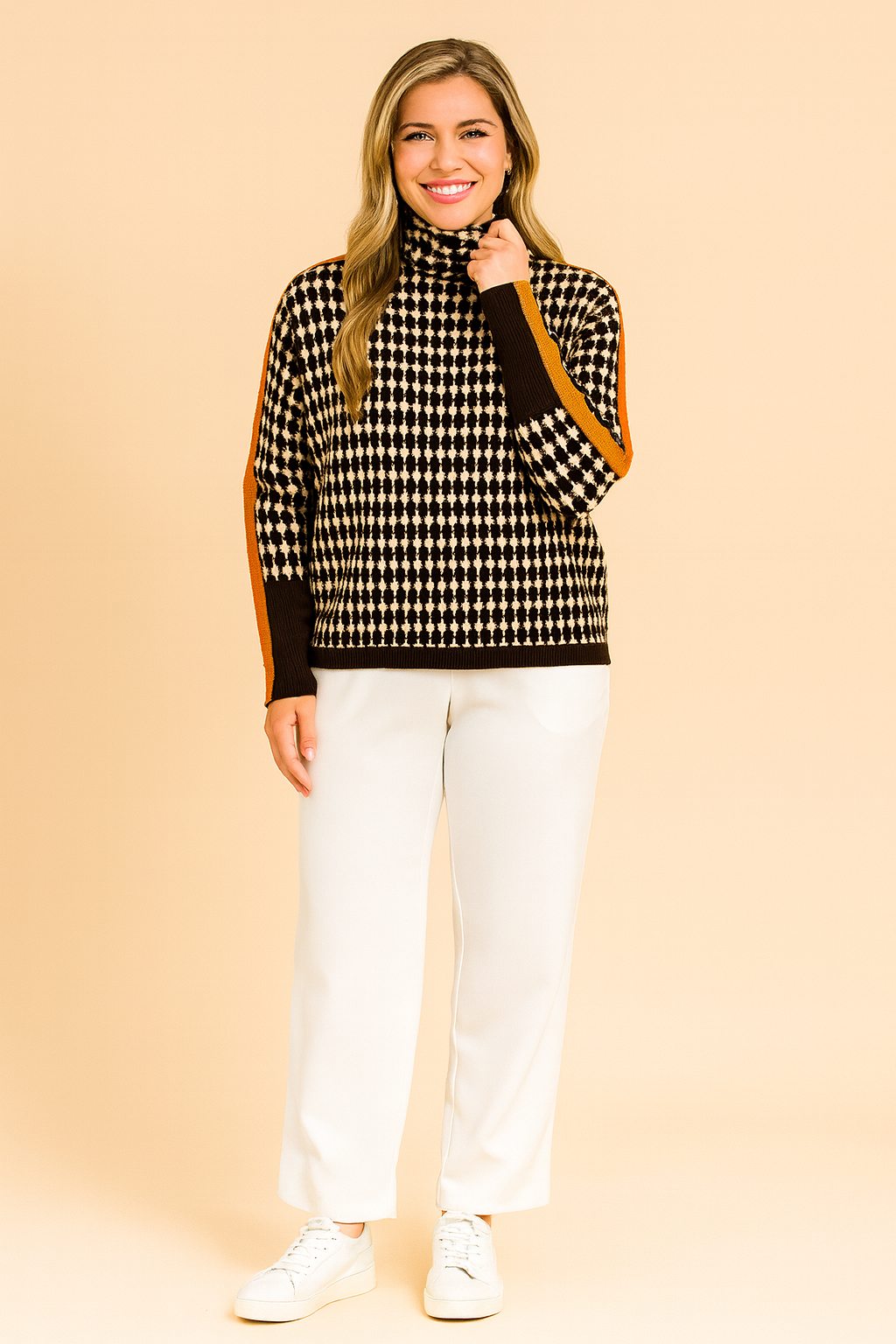 Oversized houndstooth turtleneck sweater with bold orange stripe detailing on sleeves, paired with black jogger pants and white sneakers.