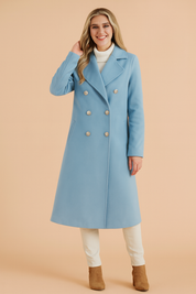 Elegant long light blue double-breasted trench coat with structured lapels, six metallic buttons, and side pockets, designed for chic winter layering