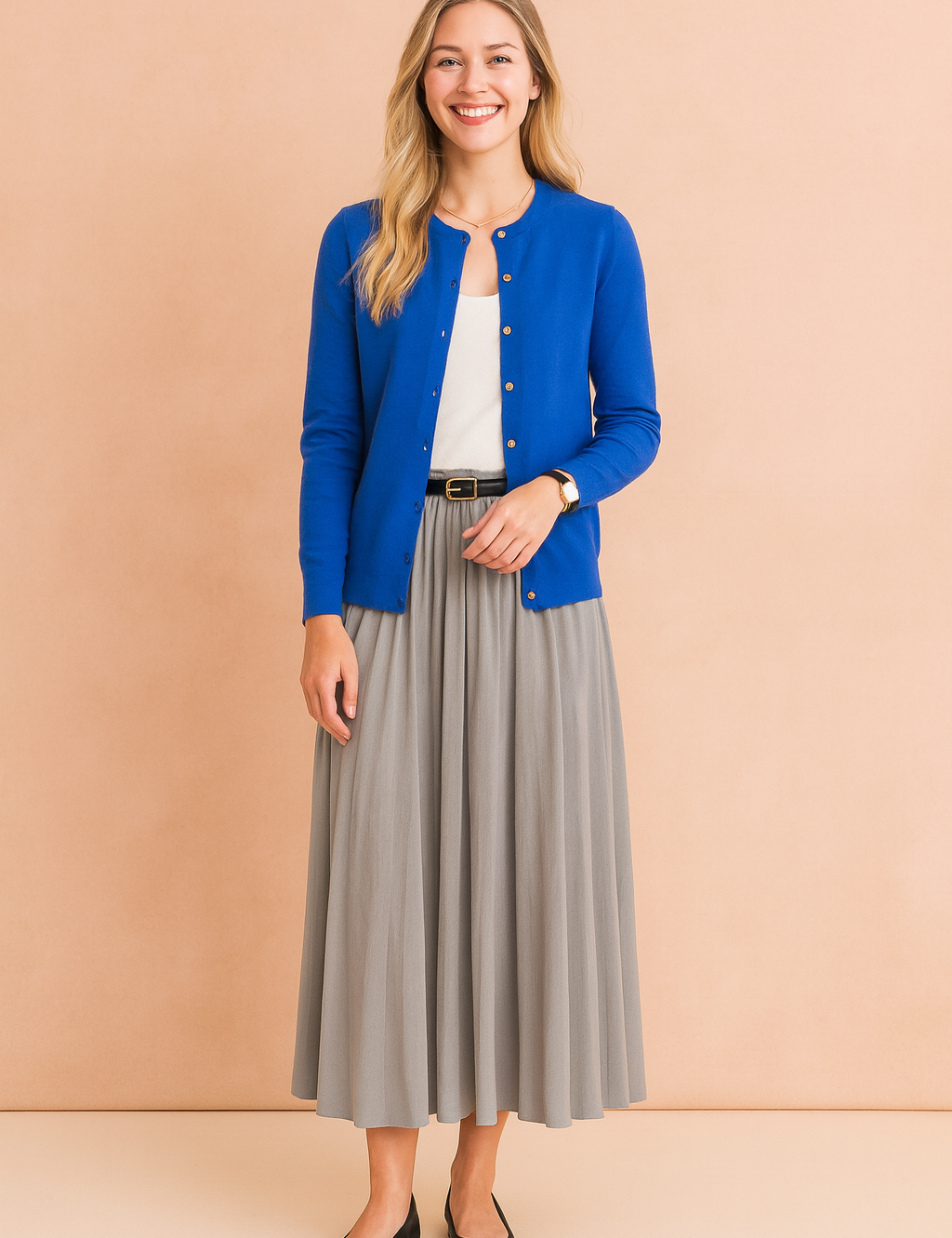 Elegant royal blue button-up cardigan paired with a white top and flowing grey pleated midi skirt, styled with a black belt and classic black ballet flats.