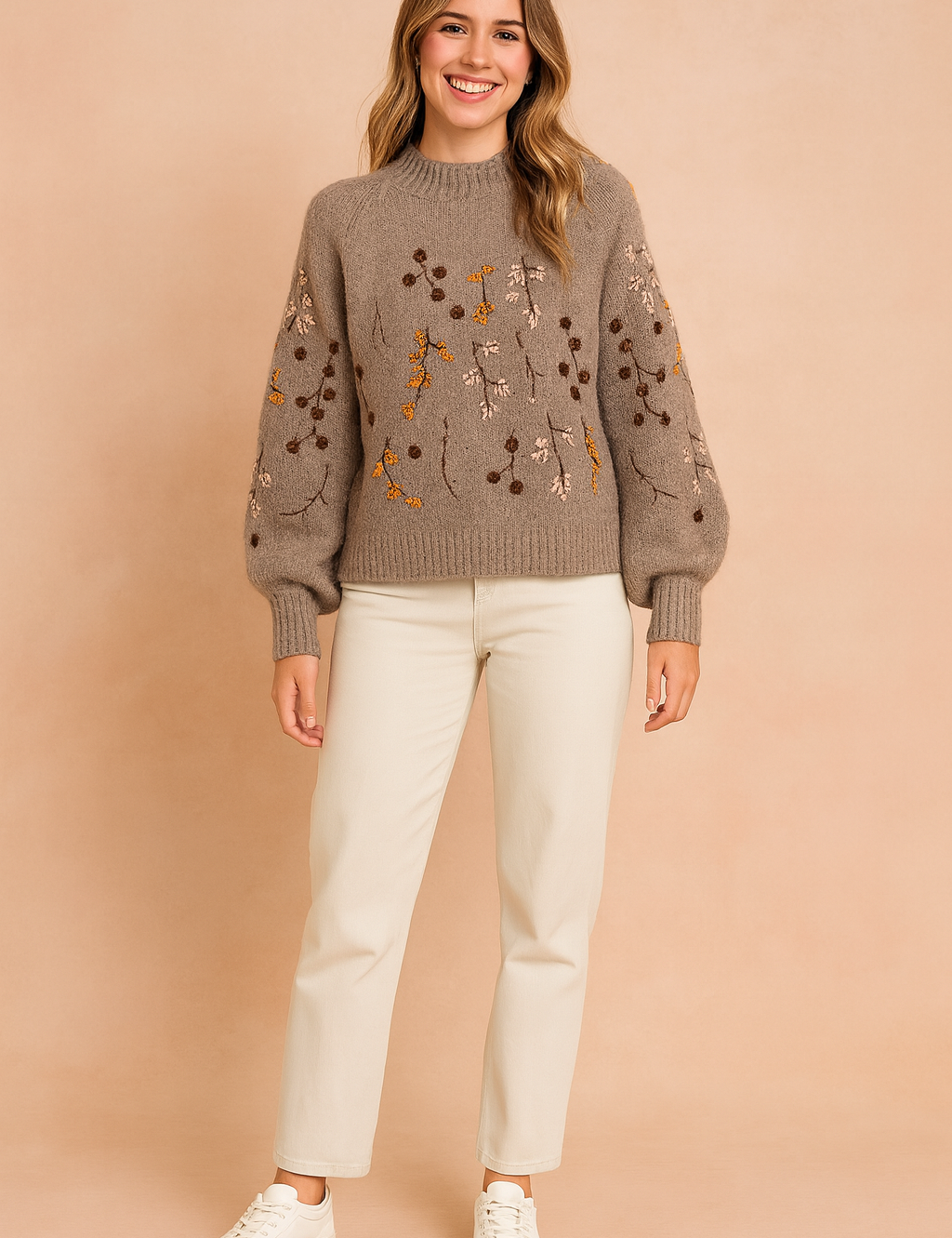 Taupe-gray knit sweater with floral embroidery in yellow, brown, and blush tones, paired with cream straight-leg trousers and white sneakers.
