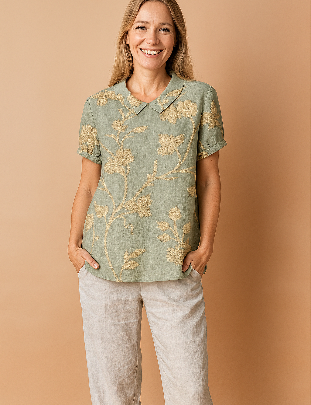 Light green linen blouse with intricate beige floral embroidery, featuring short rolled sleeves and a classic Peter Pan collar.