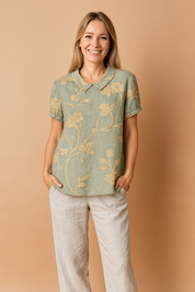 Light green linen blouse with intricate beige floral embroidery, featuring short rolled sleeves and a classic Peter Pan collar.