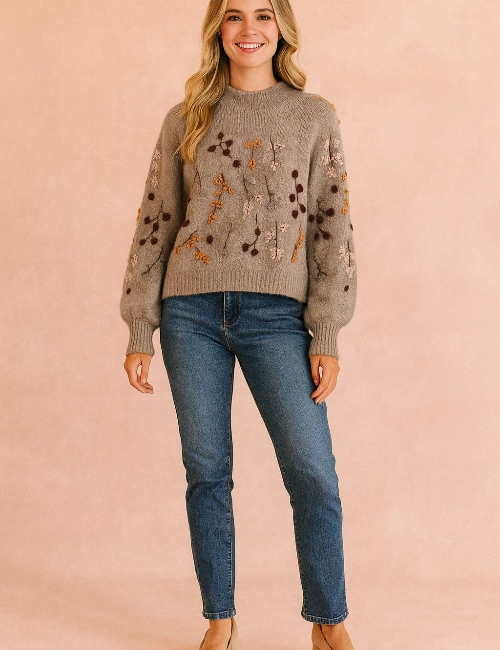 Taupe knit sweater with multicolored botanical embroidery and balloon sleeves, paired with mid-wash straight-leg jeans and beige suede block-heel pumps.