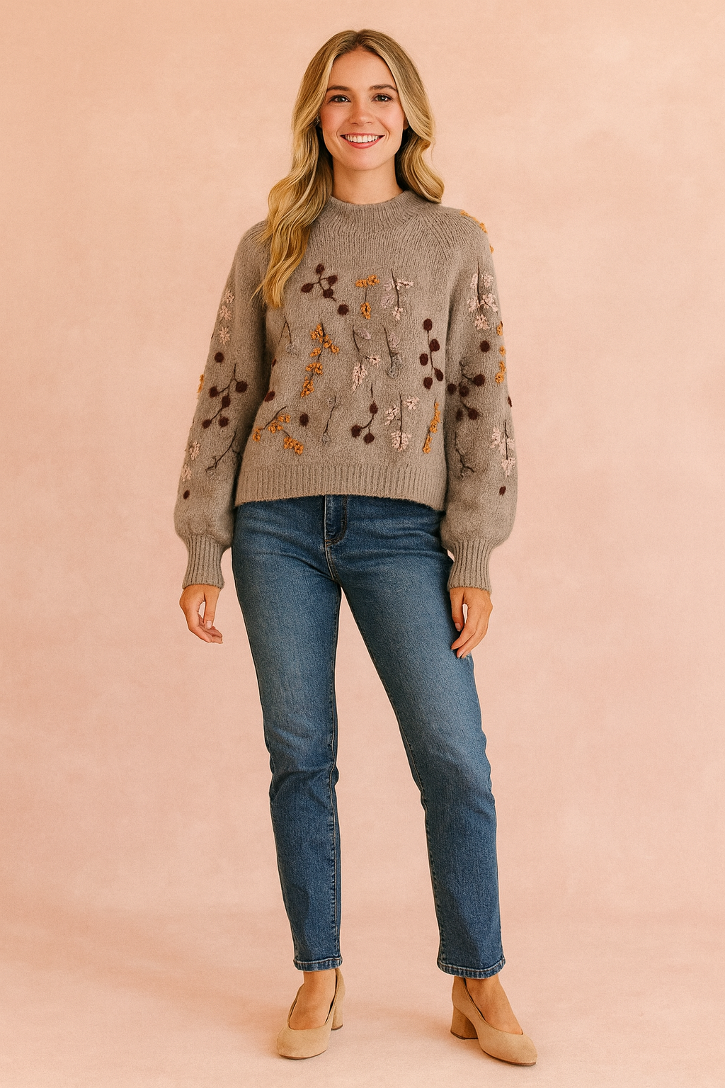 Taupe knit sweater with multicolored botanical embroidery and balloon sleeves, paired with mid-wash straight-leg jeans and beige suede block-heel pumps.