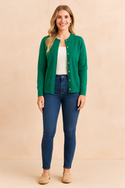 Emerald green button-front cardigan layered over a white tank top, paired with dark blue skinny jeans and beige suede loafers.