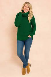 Chunky-knit emerald green turtleneck sweater paired with fitted blue denim jeans and tan suede ankle boots.