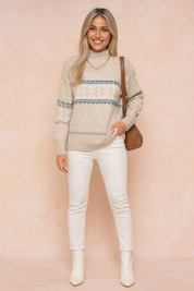 Cozy beige and white Fair Isle knit sweater with blue accents, paired with slim white jeans and cream ankle boots, accessorized with a brown leather shoulder bag.