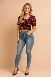 Floral crop top with bold red and pink rose print paired with high-waisted light blue skinny jeans featuring faded detailing and button closure.