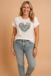 White fitted T-shirt with a colorful heart-shaped succulent and floral print, paired with high-waisted light blue denim jeans.
