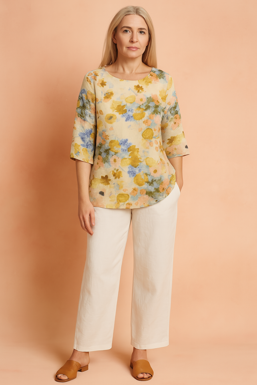Loose-fit floral blouse with yellow, blue, and peach watercolor-style print, paired with wide-leg white trousers and tan heeled sandals.