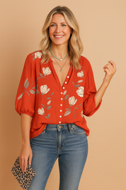 Button-up red blouse featuring a soft satin finish with white floral prints and light grey leaves, paired with mid-rise blue denim jeans.