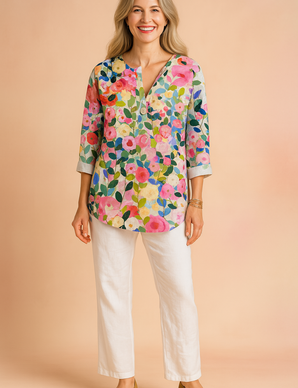 Colorful floral V-neck blouse with three-quarter sleeves, featuring a vivid multicolor garden print in pink, green, blue, and yellow tones; styled with white pants and tan block-heel shoes.