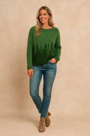 Forest green fuzzy knit sweater with dark green evergreen tree silhouette design, paired with medium-wash skinny jeans and taupe ankle boots.