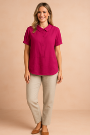 Fuchsia short-sleeve blouse with a Peter Pan collar, front button detail, and relaxed fit, paired with beige straight-leg trousers and tan closed-toe flats.