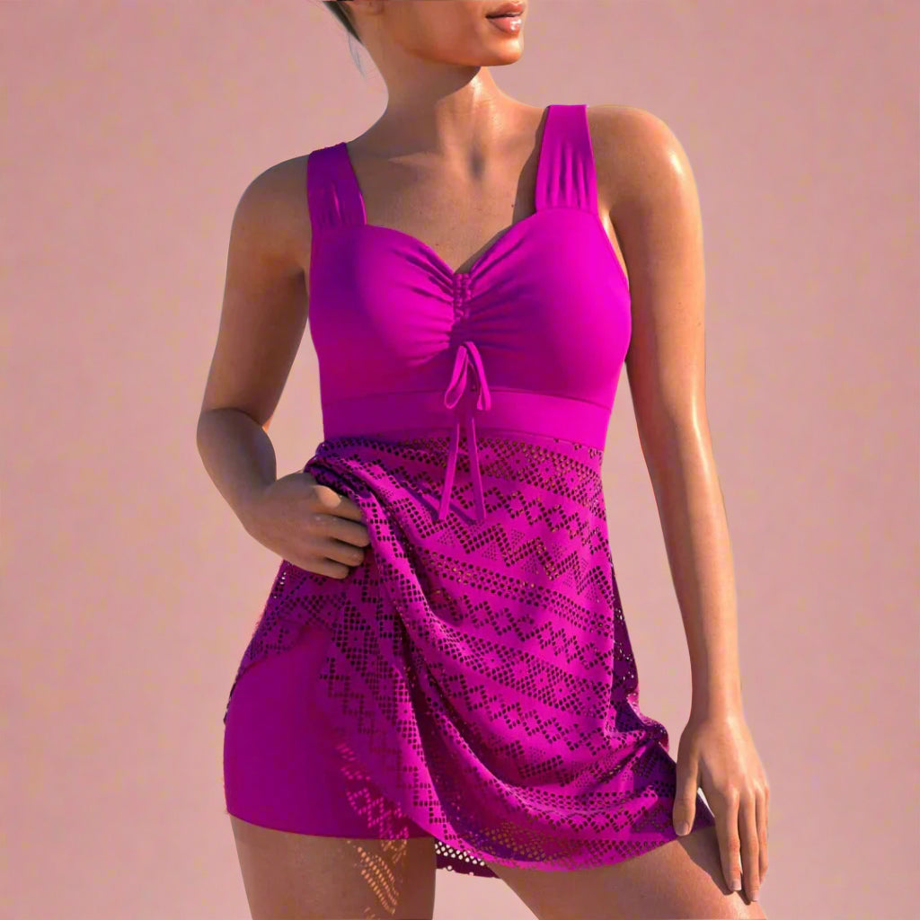 One-piece fuchsia swimsuit dress featuring a ruched V-neckline with drawstring detail and a semi-sheer geometric mesh overlay skirt. The fabric showcases a consistent diamond and zigzag pattern in darker fuchsia tones, maintaining sharp contrast and visual texture throughout the lower half.