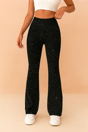 Black high-waisted flared leggings with silver glitter speckles, styled with a white cropped tank top and minimalist white platform sneakers for a modern, sporty glam look.