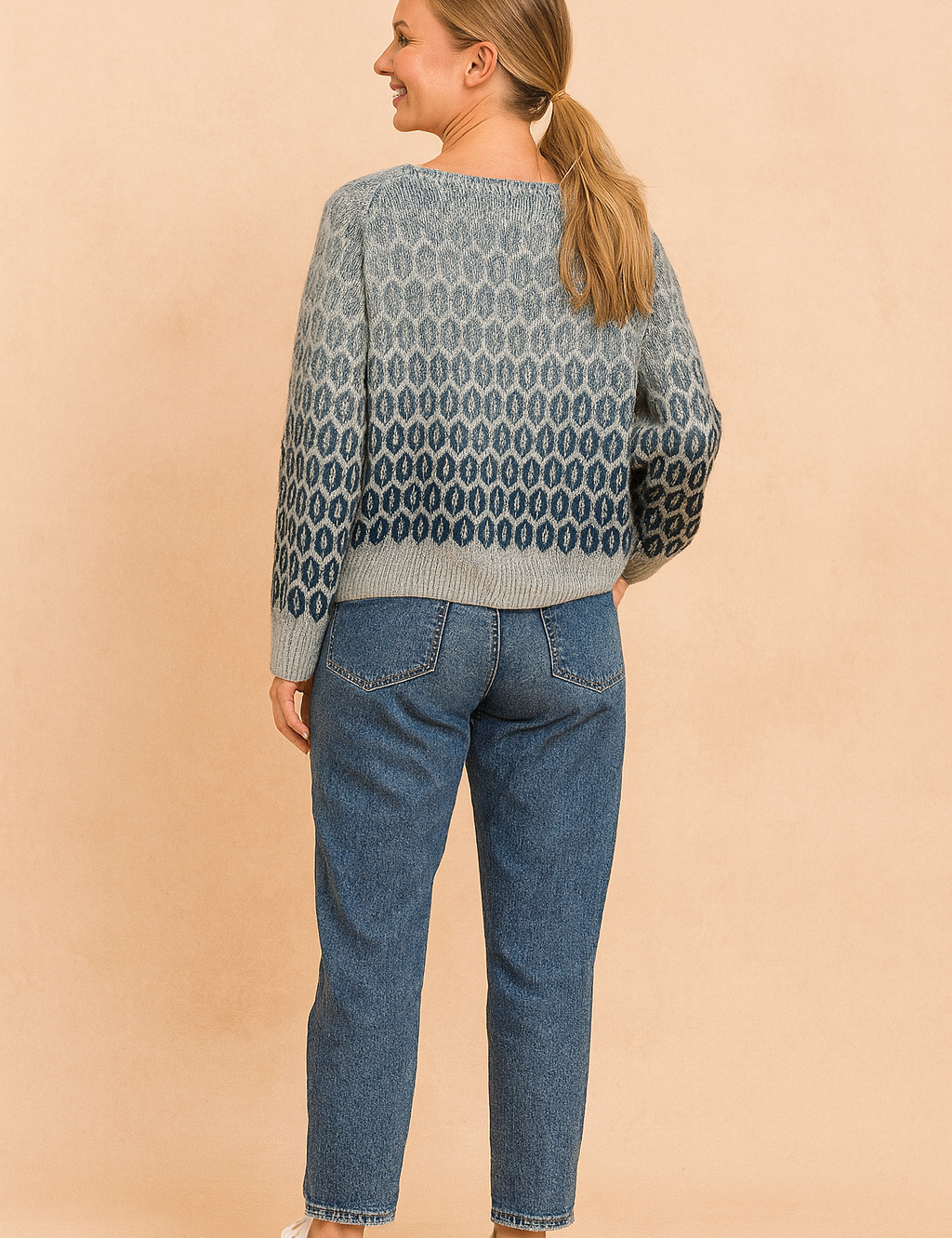 Grey to navy gradient knit sweater with oval geometric pattern on the back, paired with mid-wash straight-leg jeans and white lace-up sneakers.