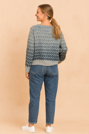 Grey to navy gradient knit sweater with oval geometric pattern on the back, paired with mid-wash straight-leg jeans and white lace-up sneakers.