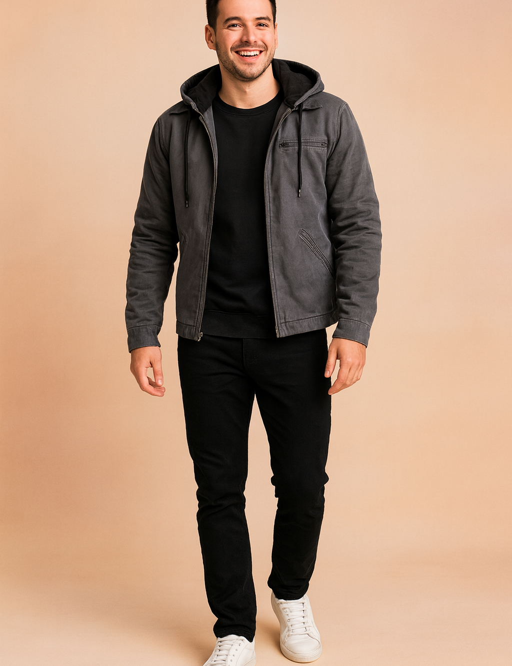 Gray hooded jacket with black fleece lining, front zipper, and drawstring details, paired with black trousers and white sneakers.