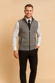 Gray zip-up knit sweater vest with front pockets, paired with a white dress shirt, black tie, navy trousers, and black leather shoes.