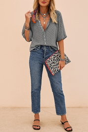 A stylish women's outfit featuring a gray textured leopard-print blouse with turquoise buttons, paired with high-rise classic blue jeans and accessorized with layered necklaces and a bold patterned clutch—perfect for chic casual wear.