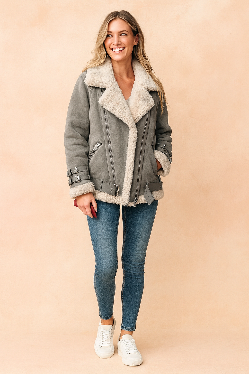 Gray shearling-lined aviator jacket with oversized lapel collar, zip closure, adjustable buckle straps on cuffs and hem, side pockets, and soft faux fur lining, styled with fitted blue jeans and white sneakers.
