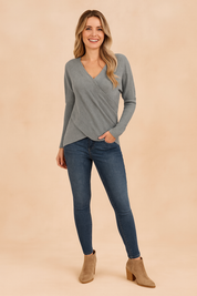 Light gray ribbed knit wrap sweater with long sleeves and asymmetrical hem, paired with dark blue skinny jeans and taupe ankle boots.