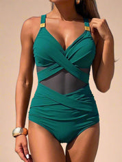 One-piece green swimsuit with crisscross bust, mesh midsection, and gold-tone strap accents