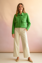 Green cropped utility jacket with front flap pockets and button closure, styled with wide-leg cream trousers and beige suede block heel shoes.