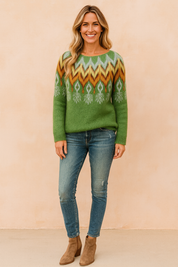 Green mohair knit sweater with multicolor Fair Isle pattern across the shoulders, paired with medium-wash fitted jeans and taupe suede ankle boots.