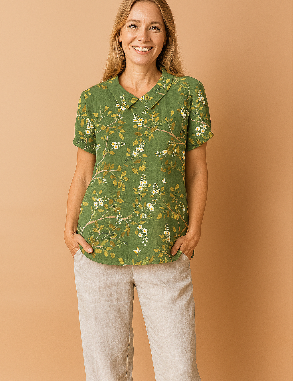 Green linen blouse adorned with a delicate yellow and white floral print, featuring short cuffed sleeves and a classic Peter Pan collar.