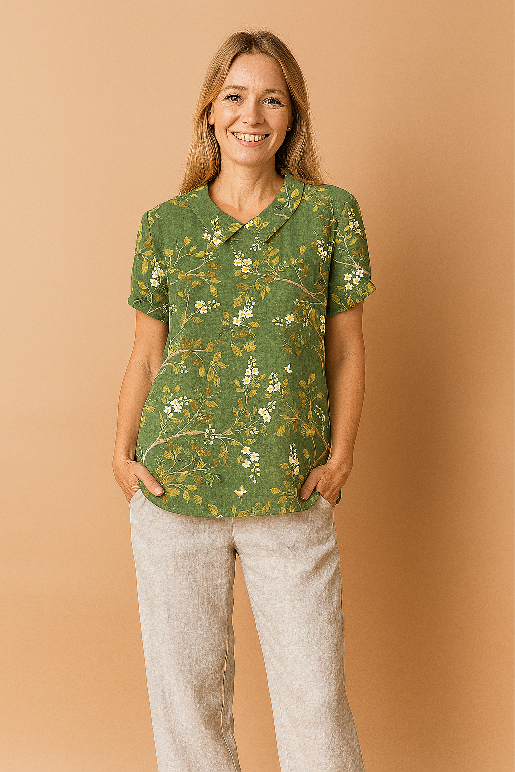 Green linen blouse adorned with a delicate yellow and white floral print, featuring short cuffed sleeves and a classic Peter Pan collar.