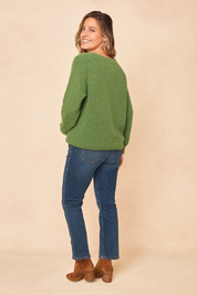 Soft green fuzzy knit sweater with a relaxed fit, paired with medium-wash straight-leg jeans and brown suede heeled ankle boots.