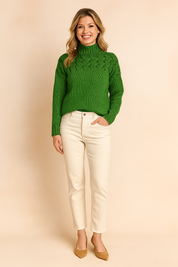 Green cable-knit high-neck sweater paired with cream high-waisted straight-leg pants and tan suede pumps.