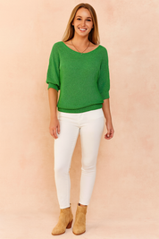 Green textured knit sweater with half sleeves paired with slim white jeans and tan suede ankle boots.