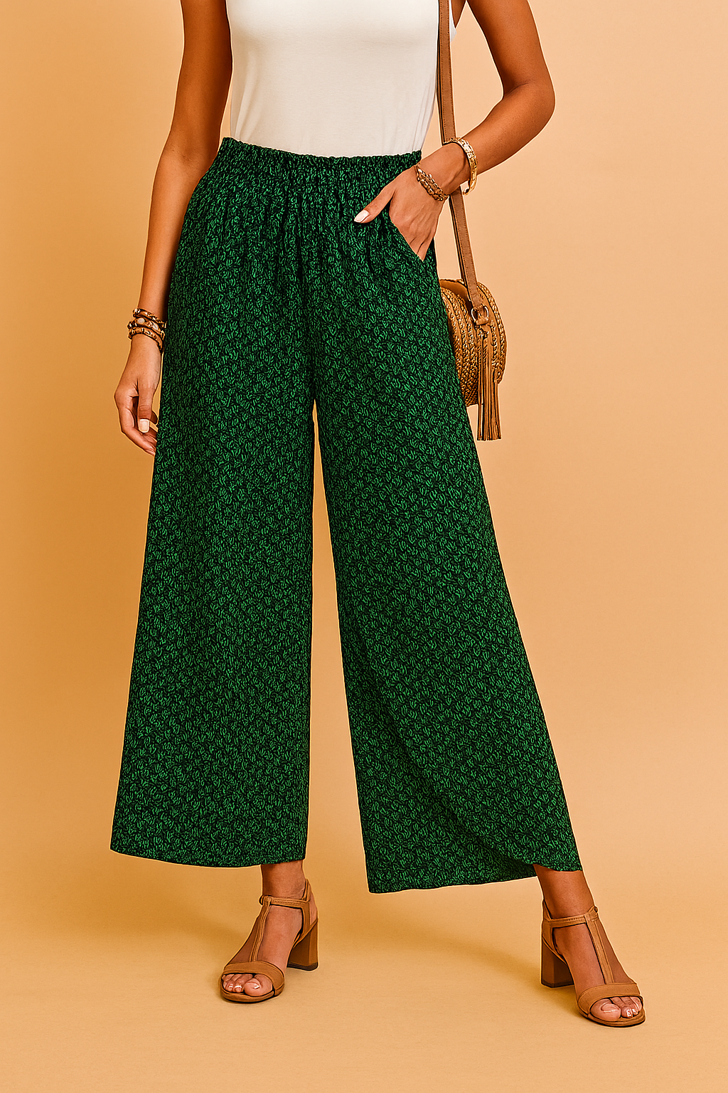Green wide-leg high-waisted pants with a subtle black leaf print, elasticated waistband, and breezy full-length cut, styled with tan block-heeled sandals and a white tucked-in sleeveless top.