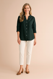 Long-sleeve forest green button-down blouse with a single chest pocket and cuffed sleeves, styled with white cropped pants and tan suede heels.