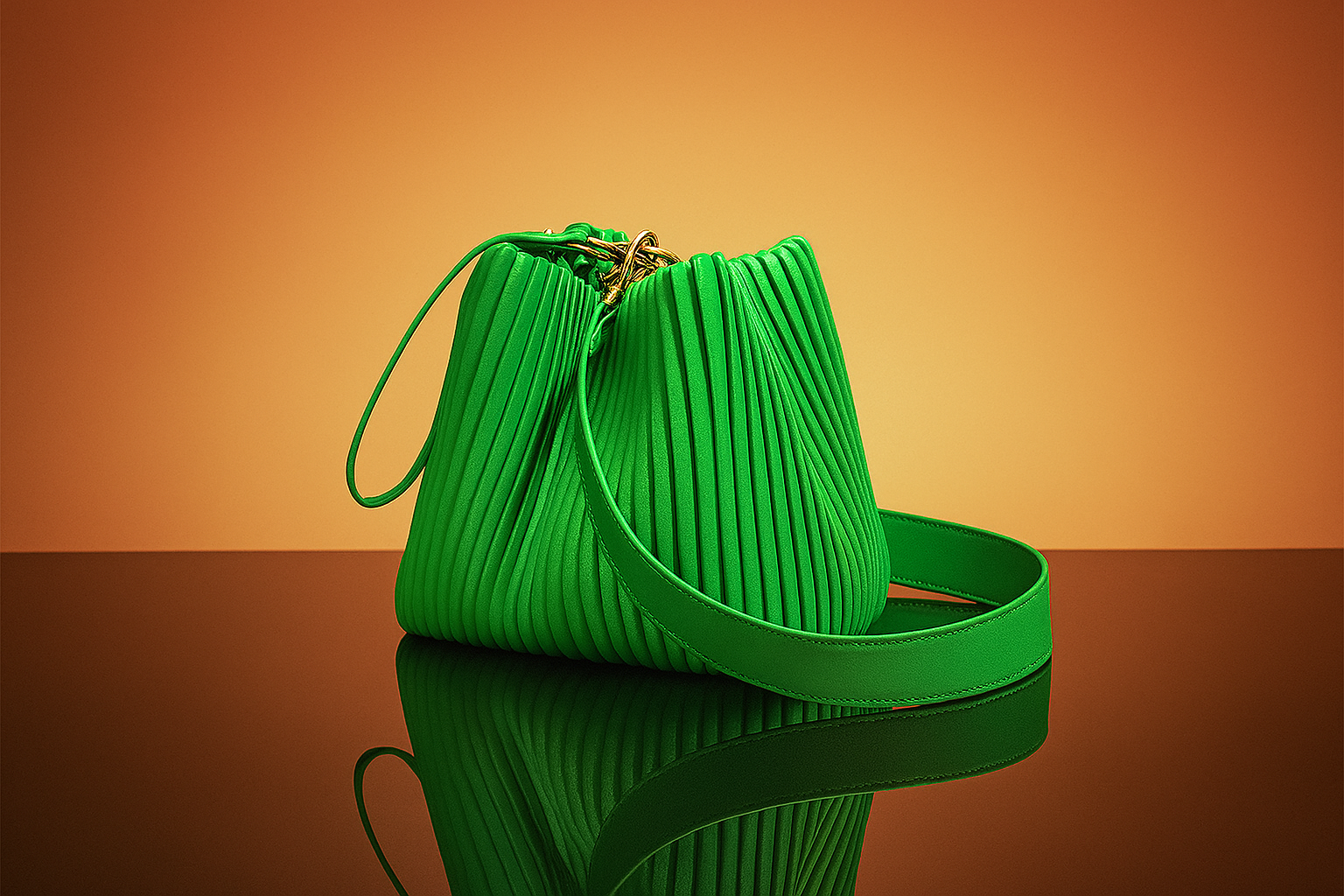 Green pleated leather handbag with gold hardware and long strap, placed on a glossy surface with warm gradient backdrop.