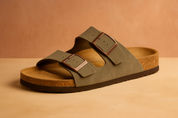  suede slip-on sandal featuring a contoured cork footbed and two wide straps with oversized brown buckles for adjustable comfort.