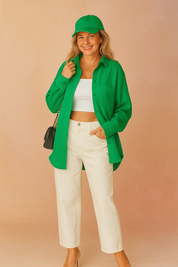 Textured bright green button-up shirt layered over a white ribbed crop top, paired with high-waisted off-white straight-leg trousers.