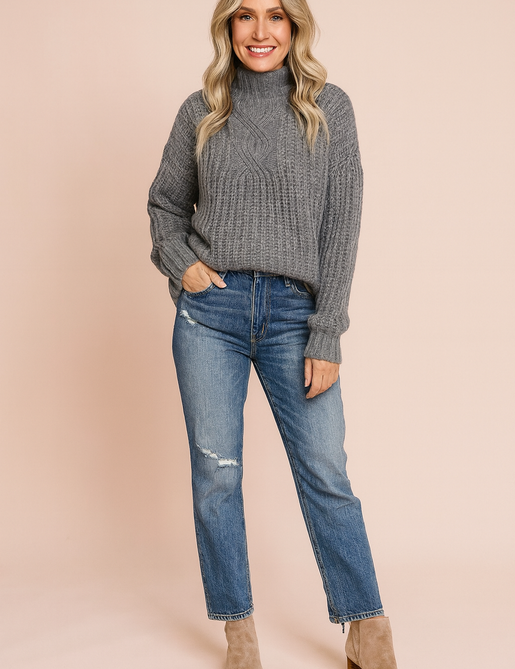 Grey cable-knit turtleneck sweater paired with distressed blue jeans and beige suede ankle boots.