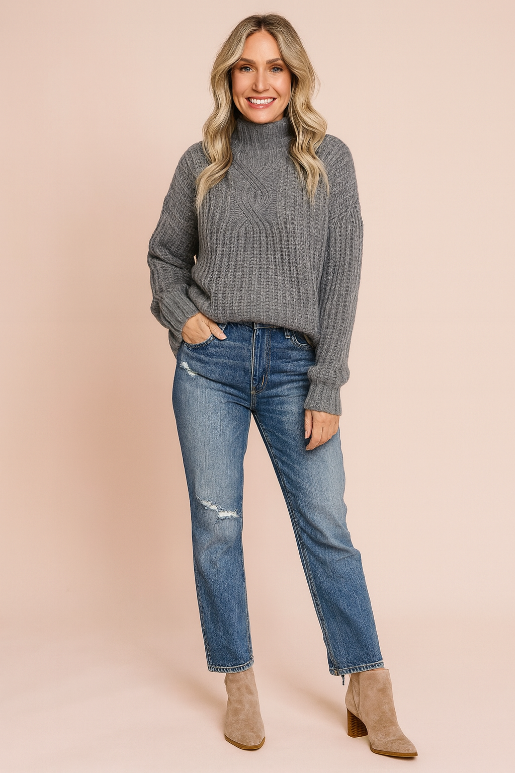 Grey cable-knit turtleneck sweater paired with distressed blue jeans and beige suede ankle boots.