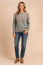 Grey knit sweater with multicolor Fair Isle pattern in pink, turquoise, yellow, and white, paired with medium-wash blue jeans and taupe ankle boots.