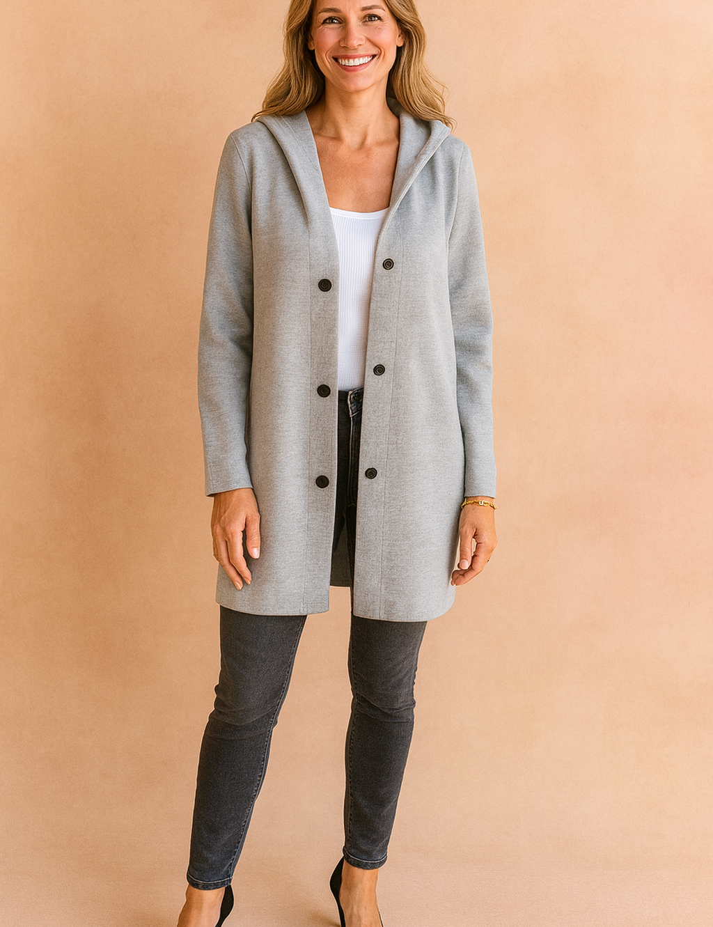 Light grey hooded longline coat with front button closure, styled over a white top and paired with fitted dark jeans and black heels for a sleek everyday look.
