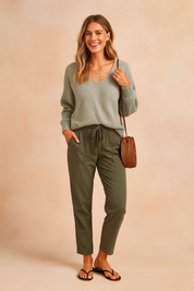 Heather grey V-neck knit sweater paired with olive green drawstring cargo pants, styled with black flip-flop sandals and a round rattan crossbody bag.