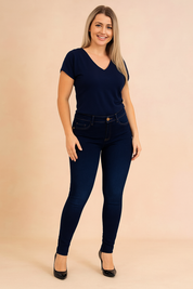 Slim-fit high-waist dark blue skinny jeans with precise stitching, button closure, and front pockets, styled with pointed black heels.
