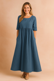 Flowy indigo-blue linen midi dress with half sleeves, a gathered waist, and side pockets in a relaxed A-line silhouette.