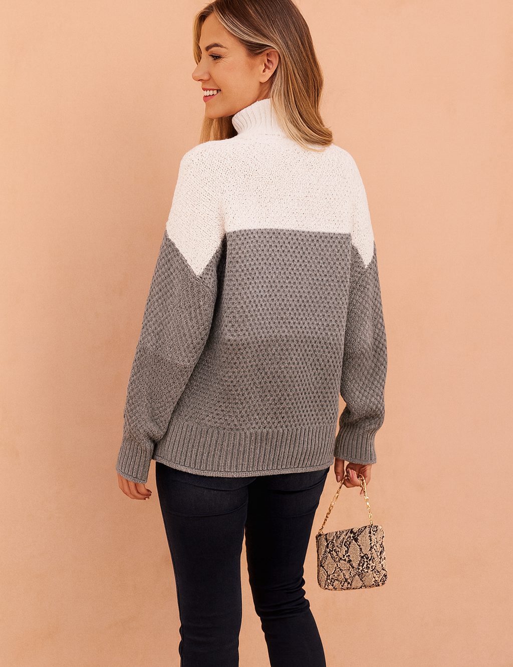 Stylish women’s tricolor knit sweater in white, light gray, and charcoal gray with a high turtleneck, paired with fitted black jeans and ankle boots.